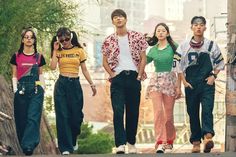 four young people walking down the street together