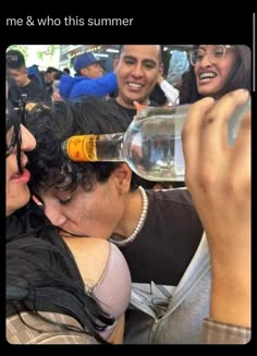 two women and one man are drinking from a wine bottle while another woman looks on