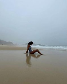 a woman sitting on the beach in her bathing suit