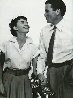 an old black and white photo of a man and woman holding hands while standing next to each other