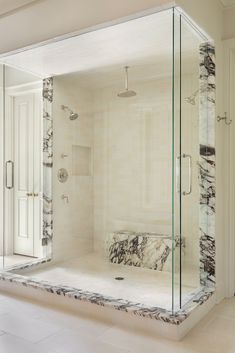 a bathroom with a marbled bathtub and walk in shower next to a white door