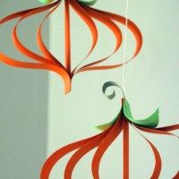 an orange and green mobile hanging on a wall next to a white wall in the background