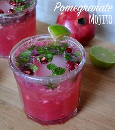 two glasses filled with pomegranate mojito on top of a wooden table