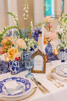 the table is set with blue and white vases filled with flowers, oranges and lemons