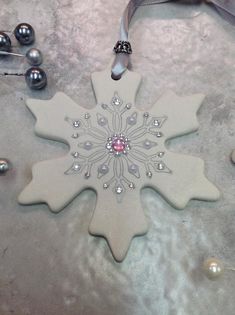 a white snowflake ornament sitting on top of a table next to ornaments