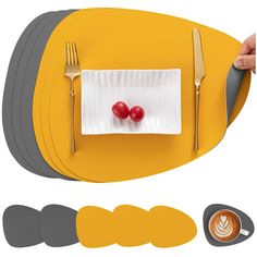 a plate with two cherries on it next to forks and spoons, along with place mats