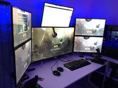 three computer monitors sitting on top of a desk next to keyboards and mouses in front of them