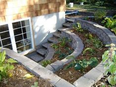 an outdoor garden area with steps leading up to the side of a house and plants growing on the ground