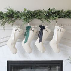 stockings hanging from the mantel decorated with greenery and personalized for guests to hang on