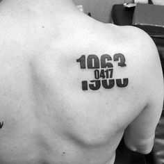 the back of a man's shoulder with numbers and letters tattooed on his chest