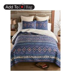 a bed with blue and white bedspread, pillows and blankets on top of it