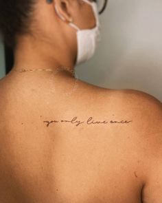 a woman with a tattoo on her back saying, you only live once in cursive writing