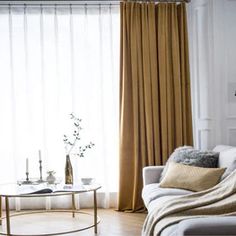 a living room filled with furniture and a window covered in drapes next to a coffee table