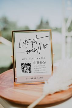 a sign that is sitting on top of a wooden table next to a white feather