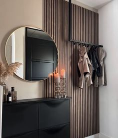 a black dresser and mirror in a room with striped wall paper on the walls behind it