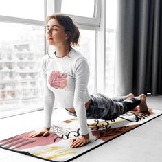 a woman is doing yoga in front of a window with her feet on the mat