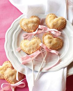 small heart shaped cookies on a plate with pink ribbon and candy lollipops