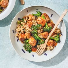 two bowls filled with broccoli and meat on top of a blue table cloth