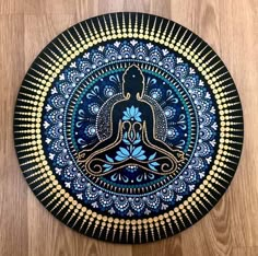 a blue and gold plate with a buddha figure on it's side, sitting on a wooden floor