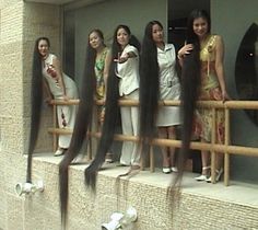 the girls are standing on the ledge with their long hair in front of them and one girl is pointing