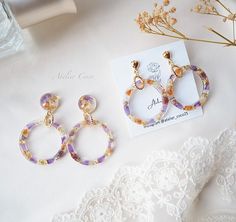 two pairs of earrings sitting on top of a table next to a lace doily