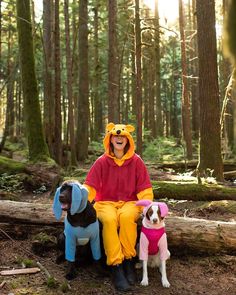 a woman in winnie the pooh costume sitting next to two dogs on a log