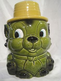 a green ceramic dog with a yellow hat on it's head