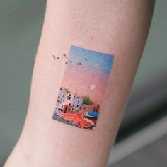 a woman's arm with a small watercolor painting on the back of it