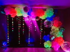 balloons and streamers are hanging from the ceiling in front of a stage set up for a party