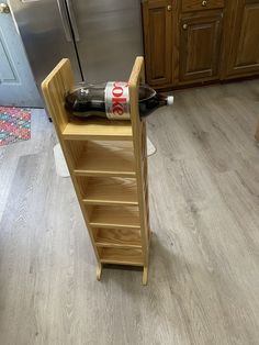 a wooden shelf with a bottle on it in the middle of a kitchen next to a refrigerator