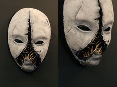 two masks with mouths and teeth are hanging on the wall, one is painted white