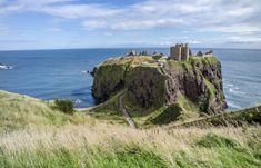 an old castle sitting on top of a hill next to the ocean