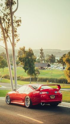 a red sports car is parked on the side of the road next to a tree