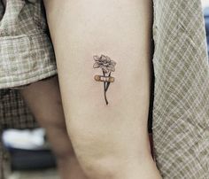 a small flower tattoo on the left inner arm and lower arm with a wine cork attached to it