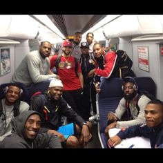 a group of young men posing for a photo on a subway train with headphones in their ears