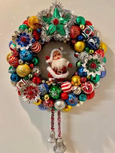 a christmas wreath hanging on the wall with santa claus in it's face and ornaments around him