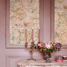 a table with flowers and candles on it in front of a wallpapered background