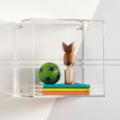 a glass shelf with some books and a toy deer