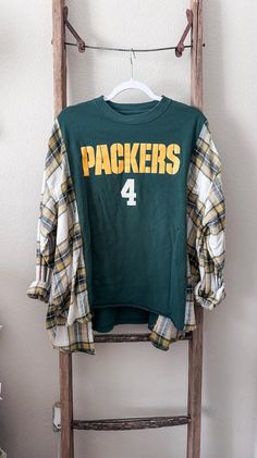 Green Bay Packers Reworked Tee/Flannel Green Bay Football Sizing: Sizing is very forgiving on these pieces. They are created to be a more oversized fit. Please see measurements and approximate sizing below. APPROXIMATE SIZE for this particular rework: Will fit sizes SMALL - 2XL PLEASE be sure to measure yourself with the provided measurements below and keep in mind that these are supposed fit a bit more oversized. MEASUREMENTS: Shoulder to Shoulder - 16" Shoulder to Bottom Hem - 25" Armpit to Armpit - 30" Our reworks are carefully pieced together with lots of love! Each piece is completely one of a kind. We use a mix of new, pre-loved and thrifted items to create each piece. Patchwork Long Sleeve Flannel Shirt For Fall, Winter Patchwork Tops For College, Plaid Cotton Sweatshirt For Fall, Casual Flannel Patchwork Tops For Fall, Upcycled Long Sleeve Tops For Fall, Thrift Upcycle Clothes, Reworked Flannel, Upcycled Tshirt, Reworked Clothes