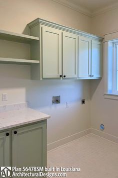 an empty kitchen with white cabinets and marble counter tops