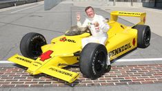 a man sitting on top of a yellow race car