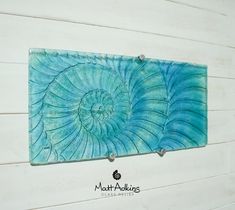 a blue wall hanging on the side of a white wooden wall with an abstract design