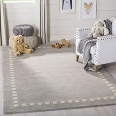 a child's room with white furniture and gray rugs, teddy bears on the floor