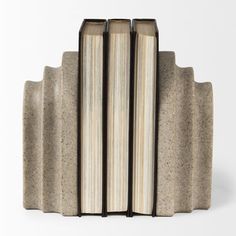 three bookends made out of concrete with books stacked on top of each other