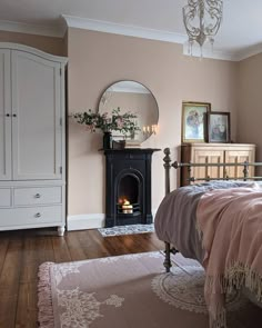 a bedroom with a bed, dresser and mirror on the wall next to a fireplace