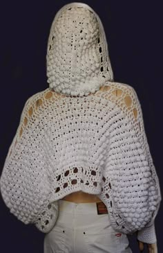 a woman wearing a white crochet sweater with an open hood and back cut out