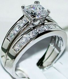 a wedding ring set with a princess cut diamond in the center and side stones on each band