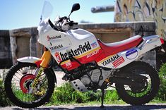 a red and white motorcycle parked next to a graffiti covered wall