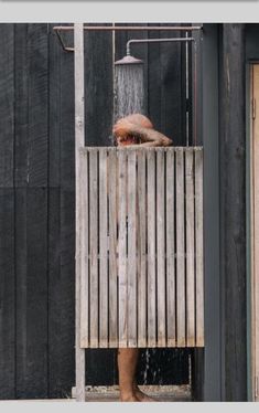 a person standing in front of a wooden structure with water coming out of the faucet