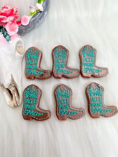 six decorated cookies sitting on top of a white fur covered floor next to a vase with flowers